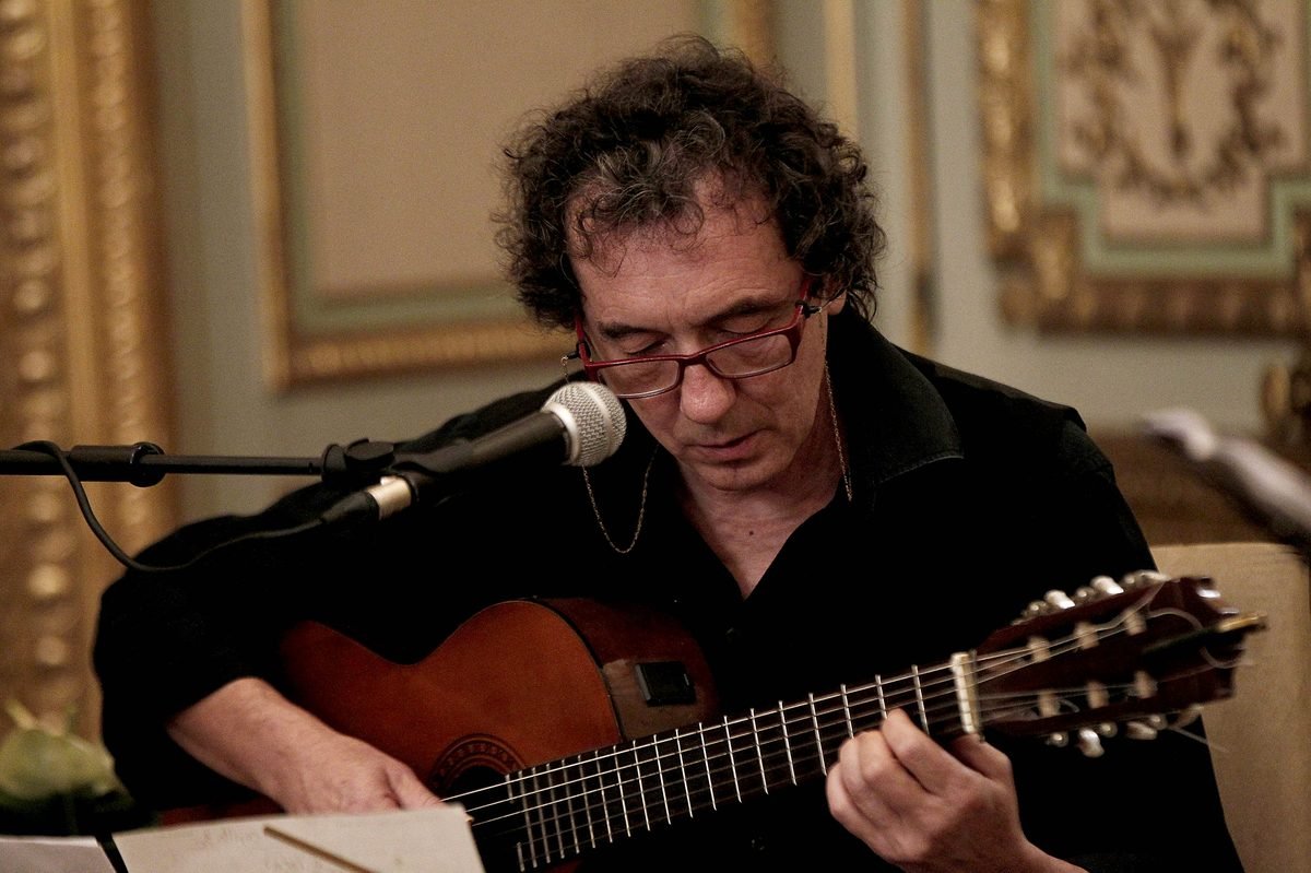Miguel Anda cantando y tocando la guitarra en un salón de molduras doradas de la Casa de América